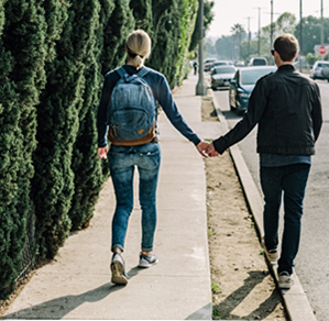 Man and Woman holding hands walking down a street, happy with their financial situation